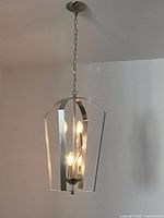 Entire chandelier hanging from ceiling showing chain mount and brushed nickel frame with four lit bulbs