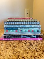 Stack of all ten cookbooks showing spines and bindings