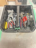 Two black bins containing mixed pliers, cutters, strippers and crimper tools
