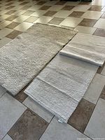 Large shag plush rug and two smaller flat-weave rugs side by side