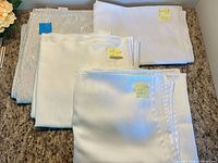 All four folded tablecloths showing color differences and size labels