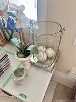 Group view of hurricane with mosaic balls, orchid arrangement, small painted vase
