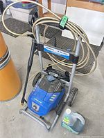 Full view of pressure washer with hose, wand and cleaner jug