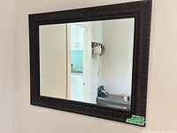 Front view of rectangular carved wood wall mirror mounted on wall