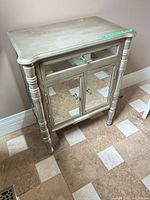 Front and side view showing mirrored panels, drawer, doors, turned legs