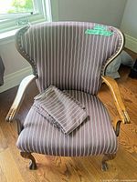 Front angled view showing striped upholstery, wood arms, claw feet, extra fabric