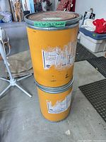 Two yellow-orange fiberboard drums stacked, showing size and exterior condition