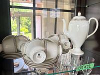 Teapot with stack of saucers and teacups showing backstamp