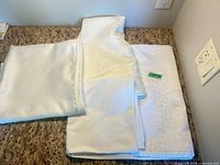 All four folded white damask tablecloths on counter