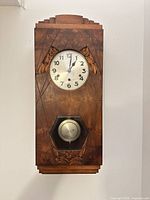Front view of wall clock showing dial and pendulum window
