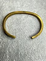 Top view of brass open cuff bracelet on fabric background