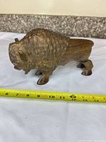 Left side view of wooden bison sculpture with tape measure showing length