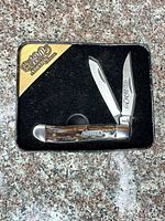 Knife in open position inside presentation tin showing both blades and handle