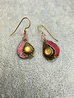 front view showing pink painted teardrop backs, brass frames and orange cabochons