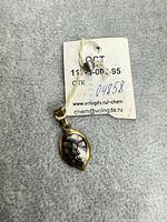 Front view of pendant with tag showing floral niello design