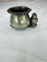 Angled view of silver-plated planter showing embossed leaf design and attached bird