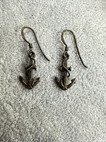 Full view of both anchor earrings with hooks displayed on fabric background
