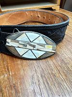 Front view of belt showing sterling buckle with mother-of-pearl inlay attached to black leather strap