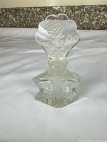 Full view of perfume bottle showing etched rose stopper and faceted base