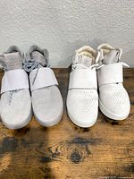 Two pairs Adidas high-top sneakers side by side, grey and white
