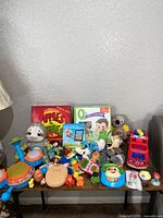 Full grouping of assorted toys on table showing board games, plush, drum set, playset and small items