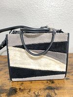 Front view showing faux shearling color-block panels, top handles, zipper