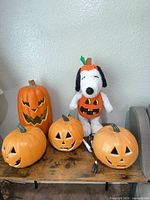 Group shot showing tall pumpkin, four small pumpkins, Snoopy plush
