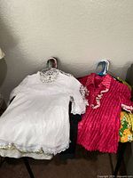 Group of tops on hangers including white lace blouse and pink crinkled blouse