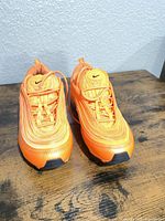 Front view of both orange Nike Air Max 97 sneakers showing laces, uppers and toe condition