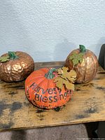 Group of three resin pumpkins on wooden surface