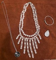 All jewelry items laid out: bib necklace, pendant necklace, teardrop pendant, bangle bracelet