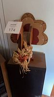 Wood flower-shaped wall hanging with raffia floral swag