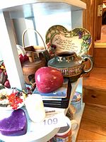 Group view on shelf showing pitcher, plaque, coasters, faux apple, candles, butter mold