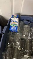 Plastic tote containing numerous clear Ball wide mouth mason jars and boxed lids
