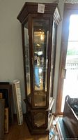 Full view of corner curio cabinet standing against wall