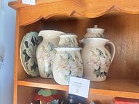 Full view of five-piece magnolia ceramic set on shelf