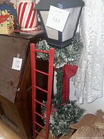 Lantern with greenery, red ladder, striped canister