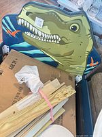 Partial assembled blue twin bed frame with green dinosaur headboard and boxed components