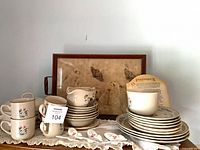 Group view of mugs, saucers, creamer, sugar bowl and plates