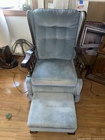 Front view of light blue wingback armchair with ottoman