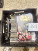 Top layer shows Star Trek comic over stack of single issues in crate