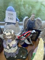 Group of assorted figurines including resin angel, ceramic praying lady, resin angel with frame, metal airplane, and white winged horse