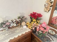 Overall dresser top view with multiple flower arrangements, candle holders and linens