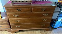 Front view of medium brown dresser showing all five drawers and hardware