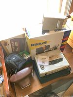 Overall view of boxed cameras, cases, accessory and slide/film box on table