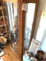 Full view of oak veneered wood and glass curio cabinet showing glass door, interior glass shelves and metal latch