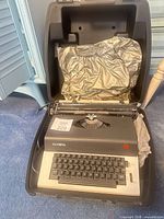 Olympia electric typewriter seated in open hard case with protective cover