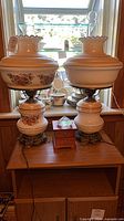 Full view of both milk glass floral lamps on table