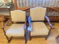 Front view of both upholstered armchairs showing fabric pattern and wood frames