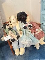 Four rag dolls seated on wooden bench, full view of outfits and sizes